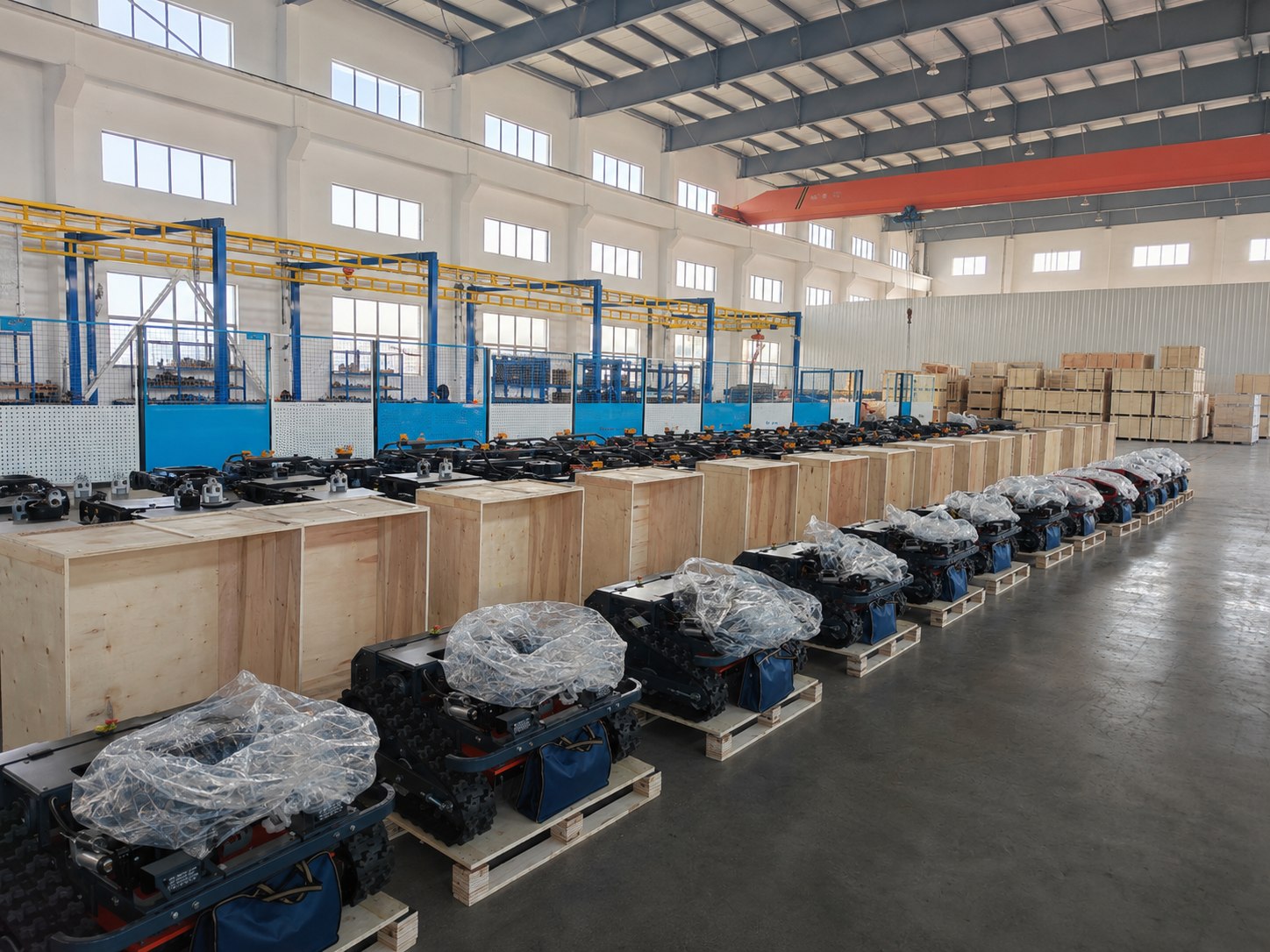 Tracked mower units covered and packed on pallets inside a factory